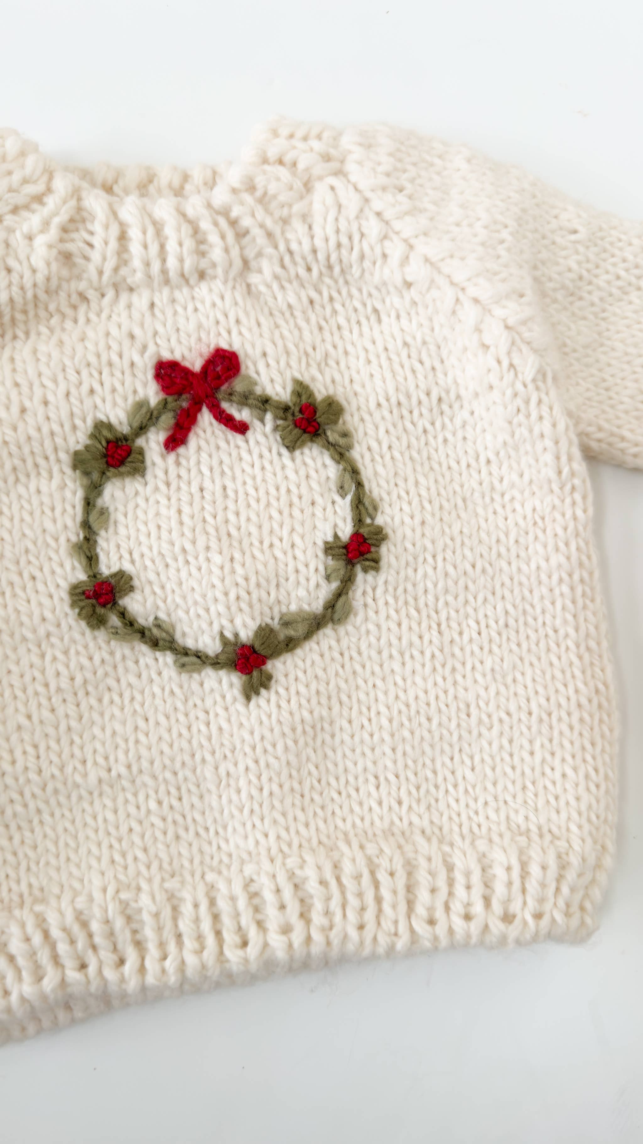 Child in the cream Wreath Sweater with embroidered wreath and red berries