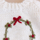 Close-up of the embroidered wreath, red berries and bow on the Wreath Sweater