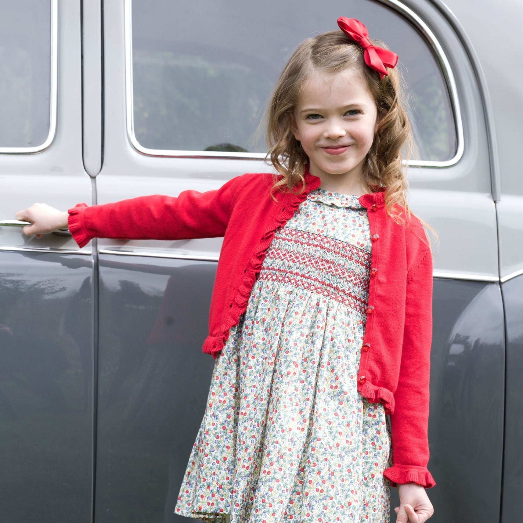 Rachel Riley Apple Blossom smocked dress styled with a red cardigan