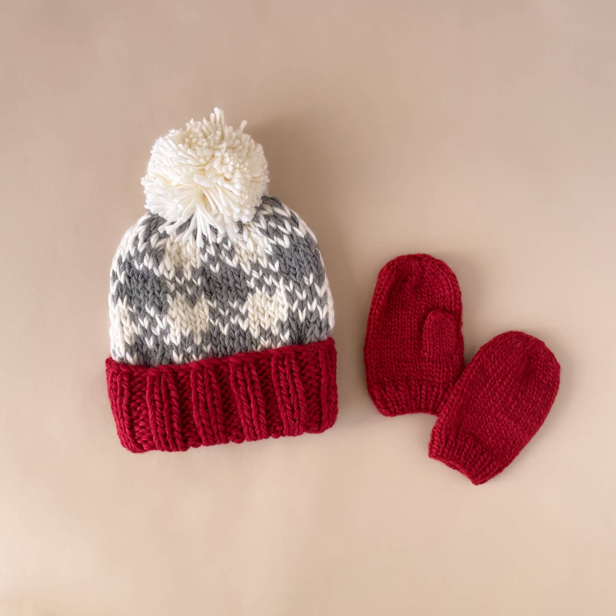 Red hand-knit baby mittens styled for winter