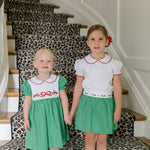 Girl wearing the Carol Christmas Skirt in green gingham with holly trim