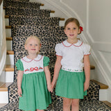 Girl wearing the Carol Christmas Skirt in green gingham with holly trim